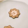 Marcasitio de madera con forma de mandala y nombre del invitado grabado en el centro, colocado sobre un plato