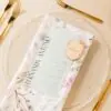 Marcasitio silvestre para bodas colocado sobre plato en una mesa decorada con flores y vajilla