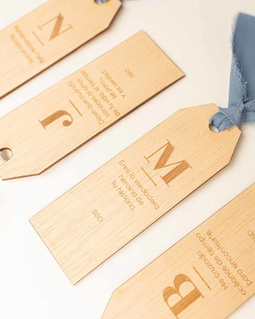 Marcapáginas personalizados con la inicial del nombre de cada invitado y sedas azules