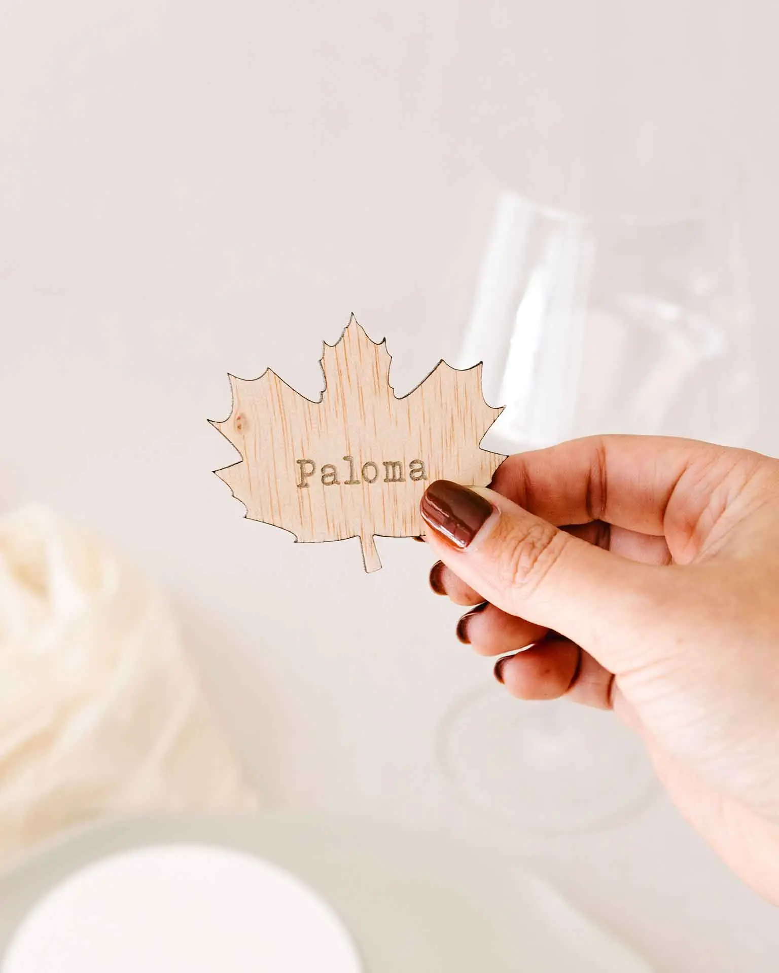 Tamaño real del marcasitio Forest mostrado en la mano, con forma de hoja grabada en madera