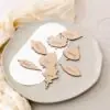 Marcasitios de madera con forma de hoja, grabados con el nombre del invitado y colocados sobre un plato