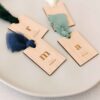 Marcasitios personalizados con inicial, nombre y lazos de seda en varios tonos, ideales como detalle de invitado
