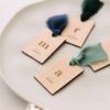 Marcasitios de madera con lazo de seda integrados en la decoraciu00f3n de mesa de boda