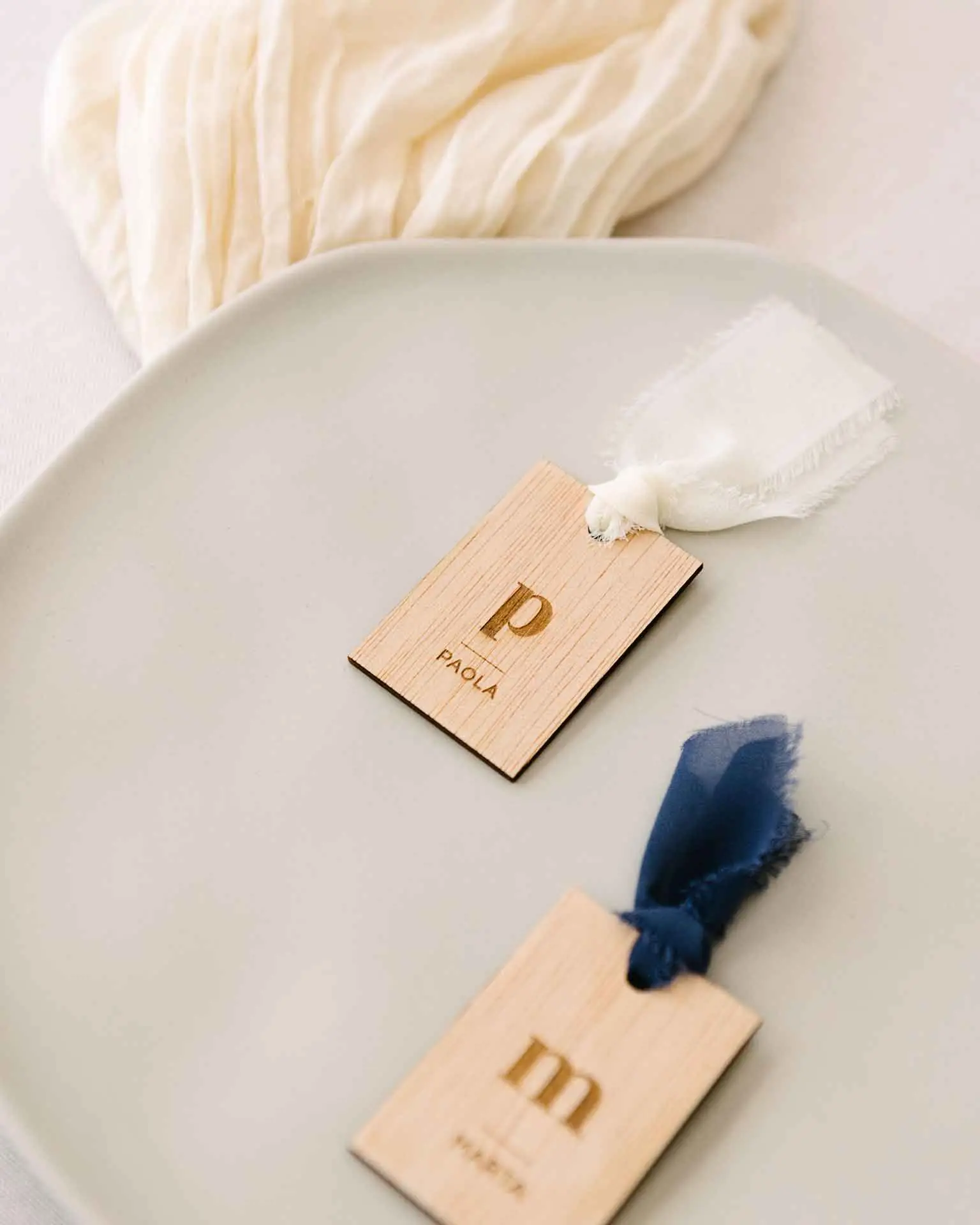 Marcasitio de madera rectangular con inicial y nombre grabado, acompañado de un lazo de seda decorativo