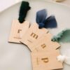 Marcasitios de madera con nombre grabado e inicial, decorados con lazos de seda en distintos colores
