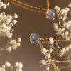 Primer plano del colgante con flor No me olvides en dorado