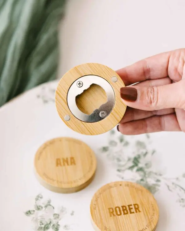 Vista en mano del abrebotellas de madera con imán y grabado personalizado para bodas