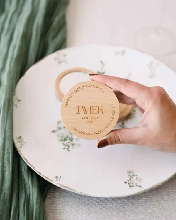 Tamaño real del espejo de bolsillo personalizado mostrado en la mano, con grabado en madera