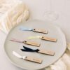 Marcasitios de madera con nombre y cinta de colores, colocados sobre una servilleta como detalle de boda
