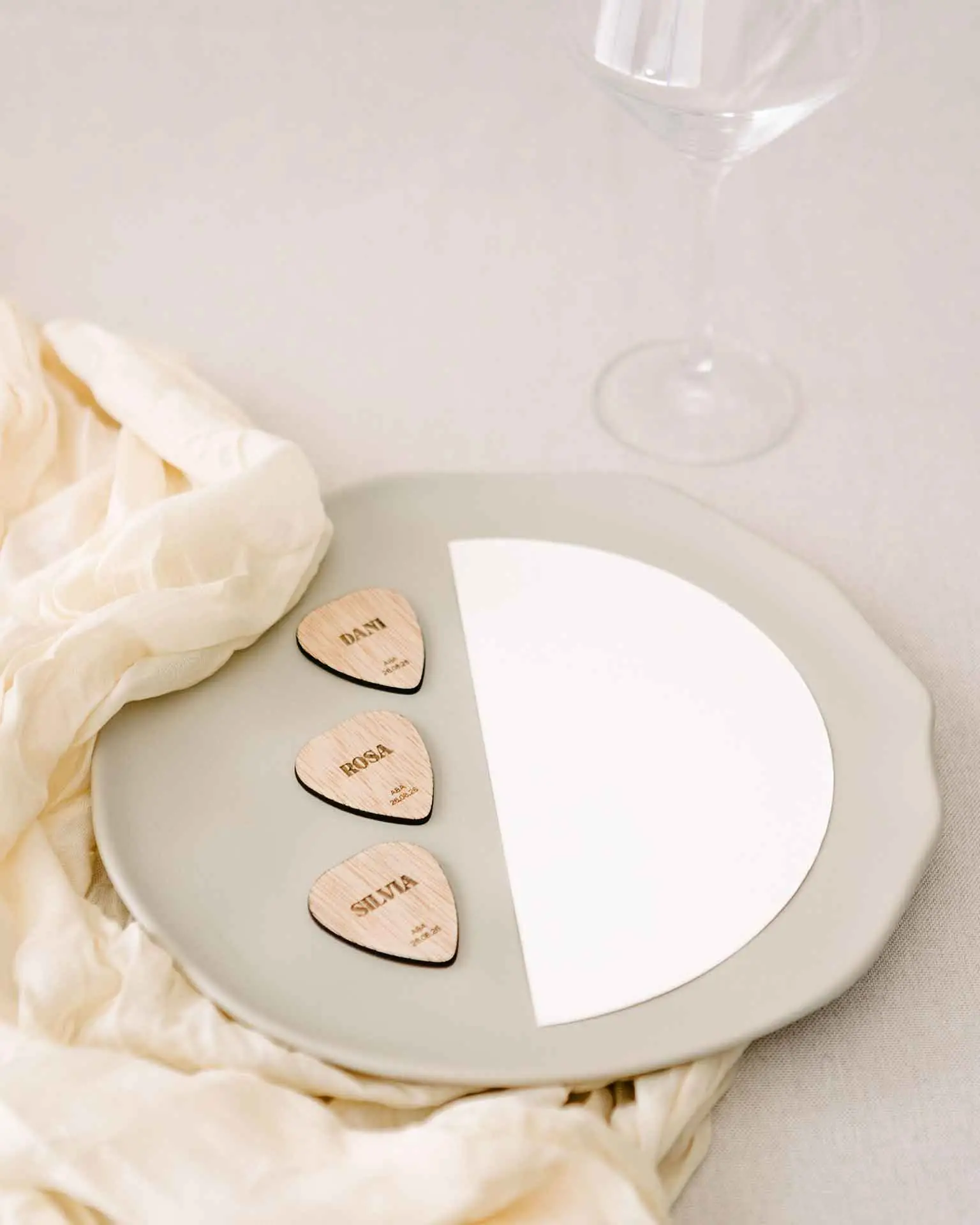 Marcasitio de madera con forma de púa de guitarra y tipografía moderna, grabado con el nombre del invitado