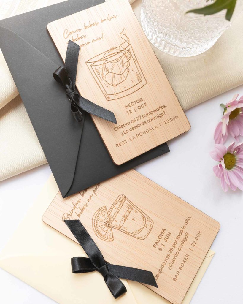 Invitación Coquette con diseño de cócteles Old Fashioned y Tequila grabados, con sobre y lazo decorativo.