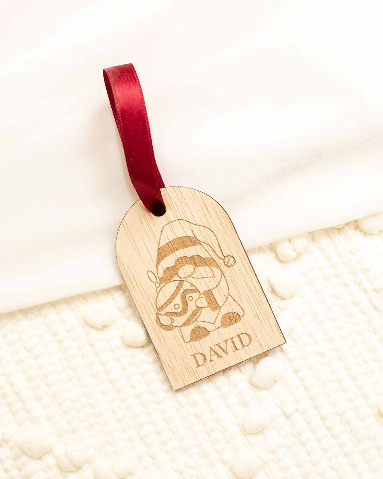 Primer plano de nombre personalizado en marcasitio navideño de madera con forma de duende
