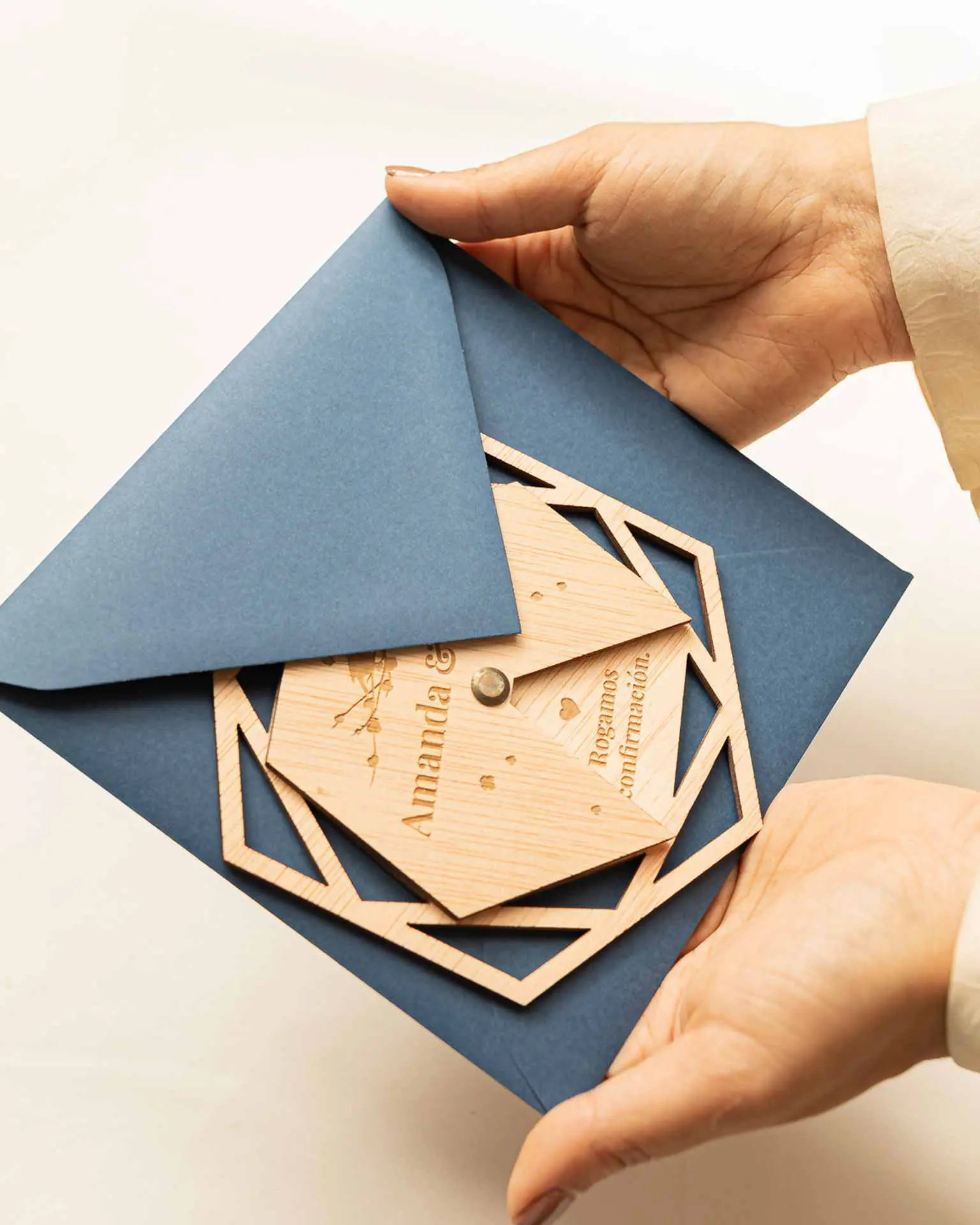 Sobre clásico para boda con invitación Nida sostenido en la mano