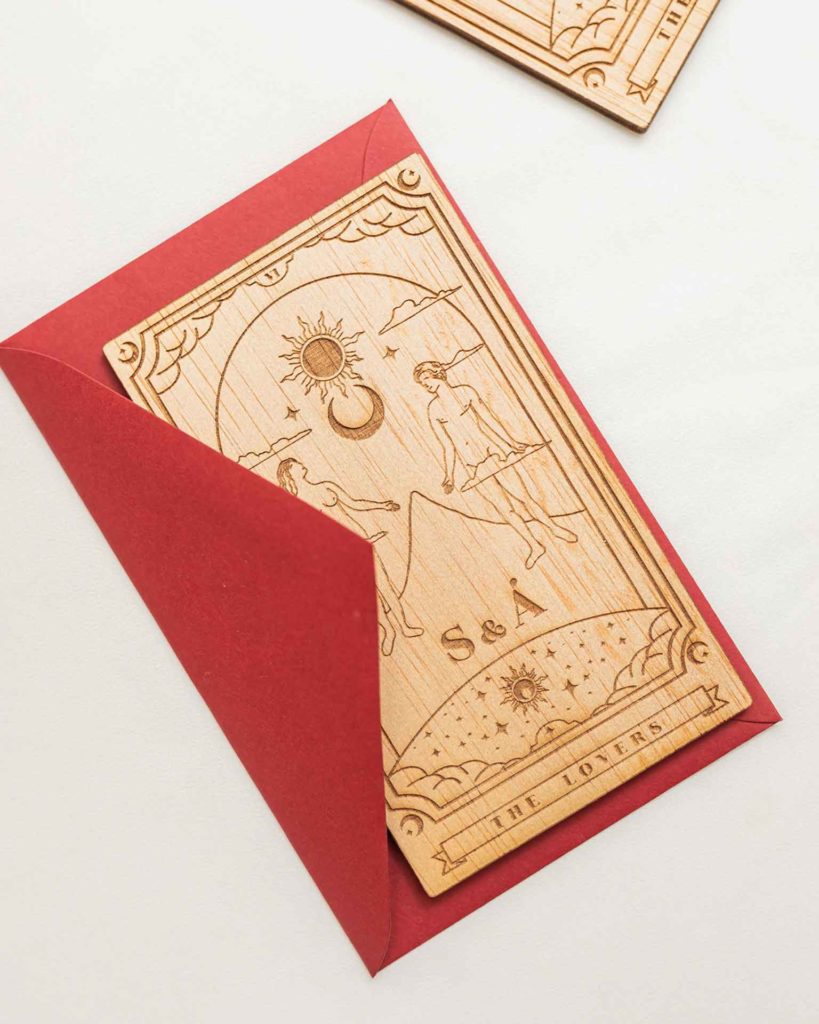 Sobre pequeño rojo para invitaciones de boda junto a la invitación Tarot