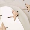 Marcasitio de madera con forma de grulla de papel origami y la inicial del invitado, colocado sobre un plato