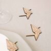 Marcasitios de madera Grulla Origami con iniciales grabadas, colocados sobre mantel en decoraciu00f3n de boda