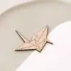 Detalle frontal del marcasitio Grulla Origami con su silueta de grulla de papel grabada en madera