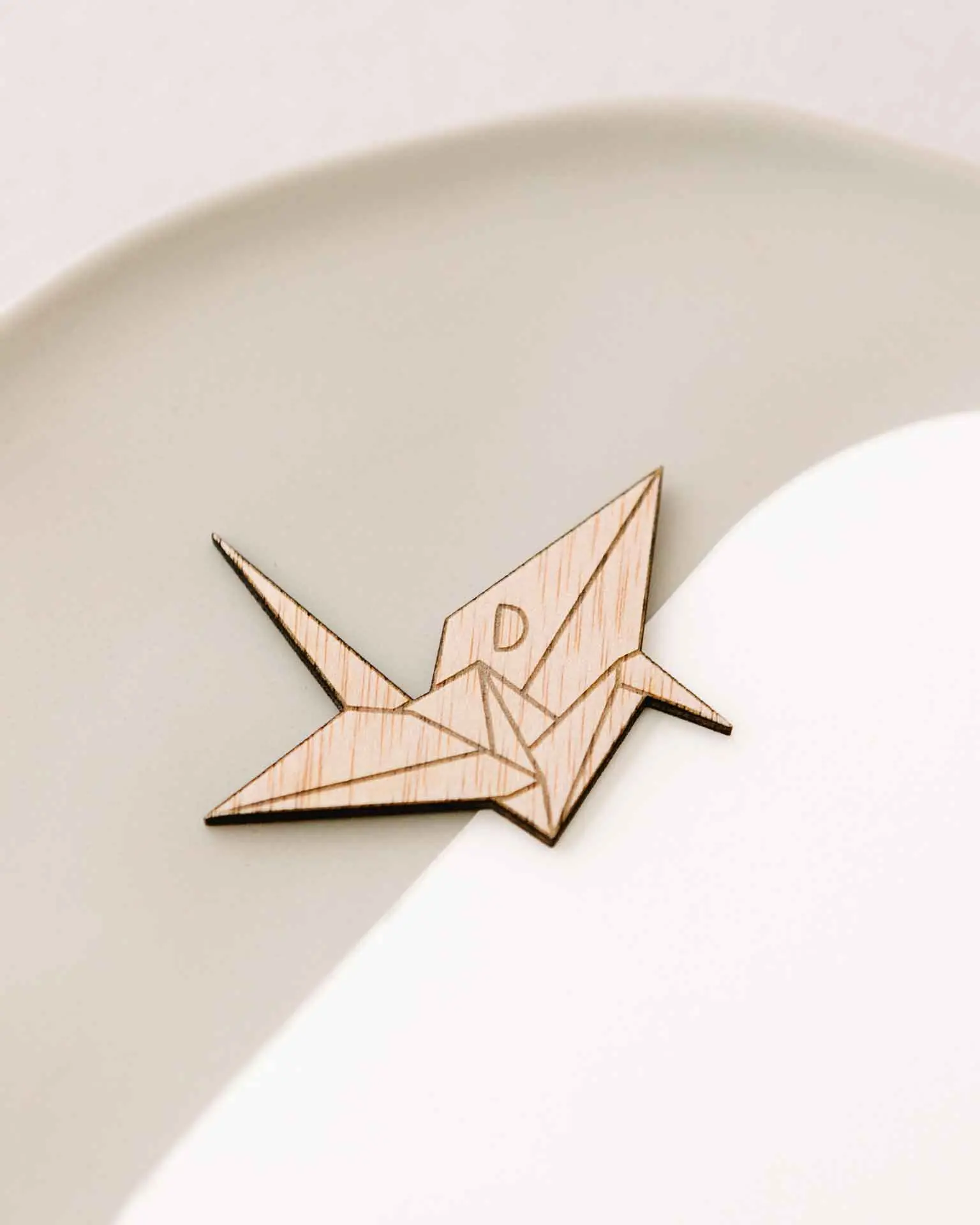 Detalle frontal del marcasitio Grulla Origami con su silueta de grulla de papel grabada en madera