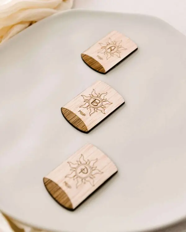 Marcasitio de madera con forma de farolillo grabado con la inicial del invitado, colocado sobre un plato