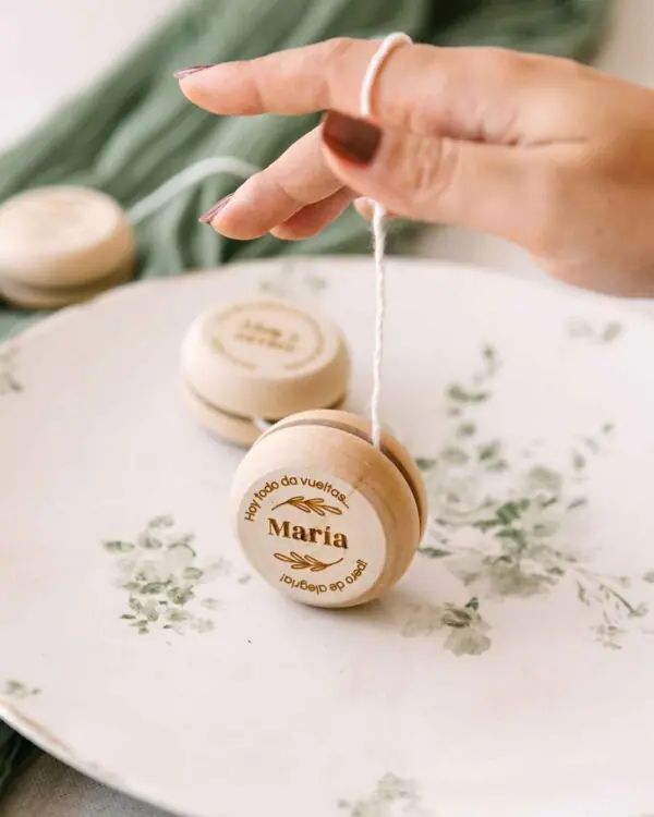 Yoyo de madera grabado sostenido en mano adulta, detalle divertido y original para invitados