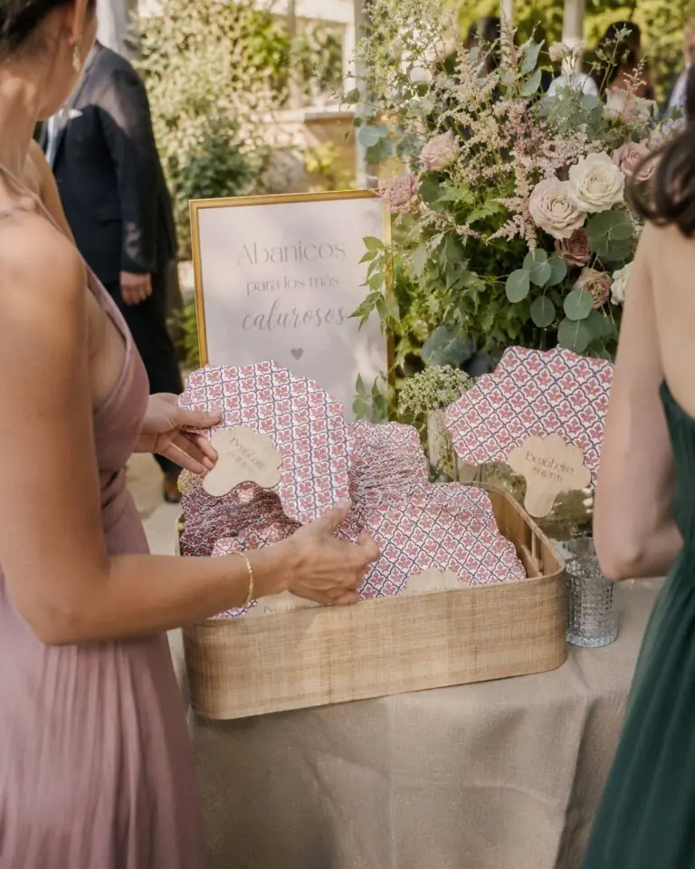 Invitadas cogiendo abanicos personalizados de una cesta en una boda