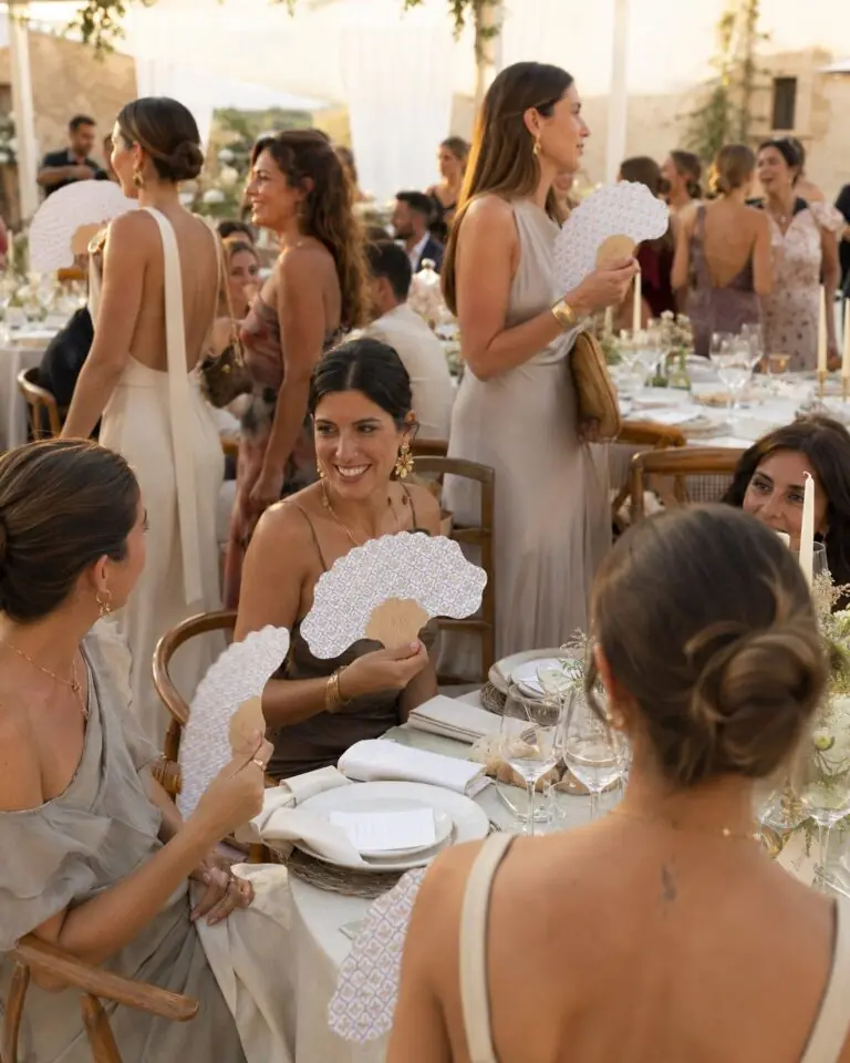 Invitadas de boda con abanicos personalizados en la mesa
